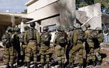 Israeli army forces stand outside a house that was hit by rockets fired by Hezbollah from Lebanon in the northern border town of Kiryat Shmona on November 26, 2024. (Photo by Jalaa MAREY / AFP)