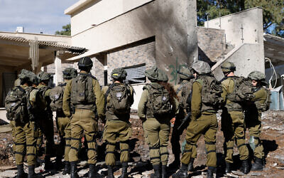 Israeli army forces stand outside a house that was hit by rockets fired by Hezbollah from Lebanon in the northern border town of Kiryat Shmona on November 26, 2024. (Photo by Jalaa MAREY / AFP)