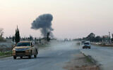 Anti-regime fighters drive along the Aleppo-Damascus M5 highway in the newly captured northwestern area of Khan al-Assal, as smoke rises in the distance on November 29, 2024 (Omar HAJ KADOUR / AFP)