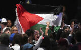 Protesters hold up a Palestinian flag as Democratic US presidential nominee Kamala Harris speaks during a campaign event at the PA Farm Show Complex and Expo Center, October 30, 2024, in Harrisburg, Pennsylvania. (AP Photo/Matt Slocum)