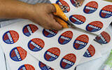 A volunteer helps cut "I Voted" stickers at the Boyle Heights Senior Center on November 4, 2024, in Los Angeles, the day before the US presidential election. (AP Photo/Damian Dovarganes)