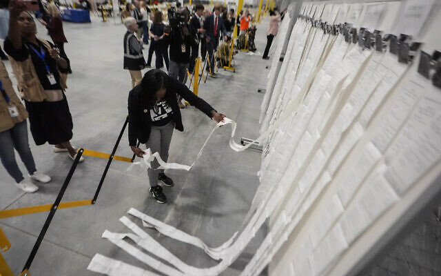 An elections staffer hangs scanner tapes used in early voting at the Fulton County Election Hub and Operation Center, November 5, 2024, in Atlanta. (AP Photo/John Bazemore) An elections staffer hangs scanner tapes used in early voting at the Fulton County Election Hub and Operation Center, November 5, 2024, in Atlanta. (AP Photo/John Bazemore)