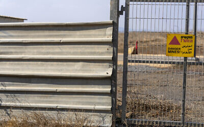 A sign warning of mines hangs on a gate in 'Trump Heights' in the Golan Heights, November 7, 2024. (AP Photo/Ariel Schalit)