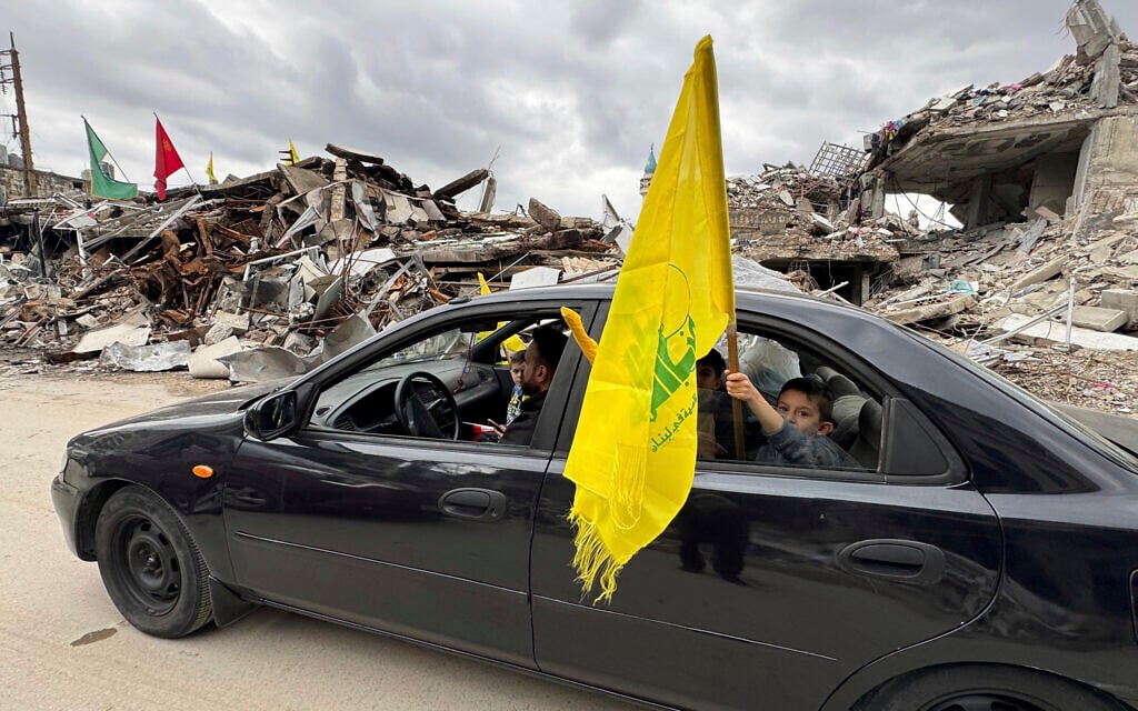 A boy holds a Hezbollah's flag, as displaced residents return to Nabatiyeh, southern Lebanon, Nov. 28, 2024 following a ceasefire between Israel and Hezbollah (AP Photo/Bassam Hatoum)