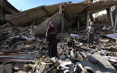 Mariam Kourani, 56, left, and her husband Ali Haidous stand on the rubble of their home after returning to the village of Hanouiyeh southern Lebanon, November 28, 2024. (AP Photo/Hussein Malla)