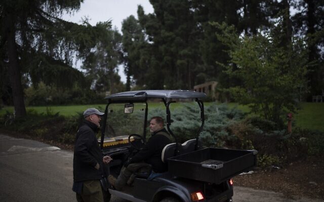 Dean Sweetland, left, talks to a neighbor in Kibbutz Malkiya in northern Israel, November 27, 2024. (AP Photo/Leo Correa)