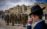 Illustrative: A Haredi man looks at Israeli soldiers gathered at the Western Wall in the Old City of Jerusalem, March 14, 2024. (Chaim Goldberg/Flash90)