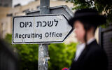An ultra-Orthodox man is seen in front of a sign for an IDF recruitment office during a protest against conscripting Haredi men to the military, in Jerusalem, May 1, 2024. (Yonatan Sindel/Flash90)