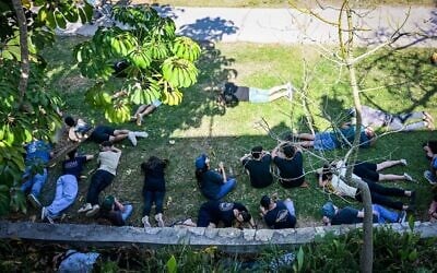 People take cover as siren warns of incoming missiles from Lebanon, during the funeral of 18-year-old Sivan Sade, who was killed by missile shrapnel while working in a field, in Kibbutz Kfar Masaryk, northern Israel, November 8, 2024. (Flash90)