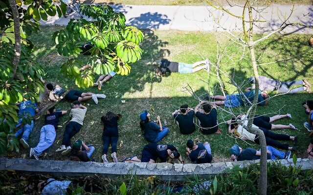 People take cover as siren warns of incoming missiles from Lebanon, during the funeral of 18-year-old Sivan Sade, who was killed by missile shrapnel while working in a field, in Kibbutz Kfar Masaryk, northern Israel, November 8, 2024. (Flash90)