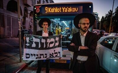 Ultra-Orthodox protesters hold up a sign reading, 'We will die and not enlist,' while blocking a road during a protest against army recruitment, in Bnei Brak, November 17, 2024. (Erik Marmor/ Flash90)
