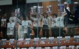 Hostage families hold up photos of their loved ones in the gallery of the Knesset on November 18, 2024. (Photo by Chaim Goldberg FLASH90)