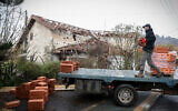 A man unloads construction materials in front of a damaged building in Metula, November 27, 2024. (David Cohen FLASH90)