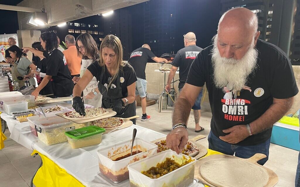 Hostage father Dani Miran, far right, with a long beard grown while his son is held hostage, works with other volunteers at a pizza dinner he organized at the Hostages Forum in November 2024 (Jessica Steinberg/Times of Israel) Hostage father Dani Miran, far right, with a long beard grown while his son is held hostage, works with other volunteers at a pizza dinner he organized at the Hostages Forum in November 2024 (Jessica Steinberg/Times of Israel)