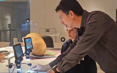 Dr. Anit Reim and Nehorai Nir examine the medallion by microscope, in a photo released on December 29, 2024. (Elisheva Zvibel/Israel Antiquities Authority)