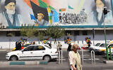 Iranians cross a road under a billboard bearing portraits of the late founder of the Islamic Republic Ayatollah Ruhollah Khomeini (R) and the current Supreme Leader Ayatollah Ali Khamenei in the capital Tehran on August 27, 2024. (Photo by ATTA KENARE / AFP)