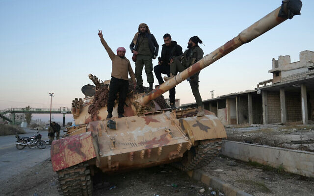 Anti-government fighters pose for a picture on a tank on the road leading to Maaret al-Numan in Syria's northwestern Idlib province on November 30, 2024. (Muhammad Haj Kadour / AFP)
