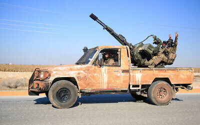 Anti-government fighters ride military vehicles as they drive along a road in the eastern part of Aleppo province on December 1, 2024. (Aref TAMMAWI / AFP)