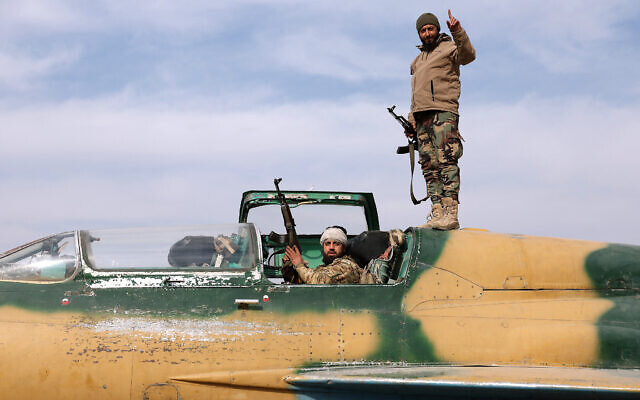 Anti-government fighters gesture as they check a Syrian military jet after they took over an airbase near the central city of Hama, on December 6, 2024. (Omar Haj Kadour/AFP)