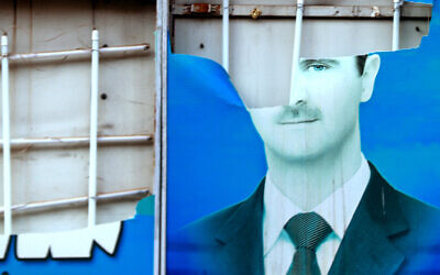 A damaged portrait of Syrian President Bashar al-Assad hangs in the city of Qamishli, as Syrian Kurds celebrate the fall of capital Damascus to anti-government fighters on December 8, 2024. (Delil SOULEIMAN / AFP)