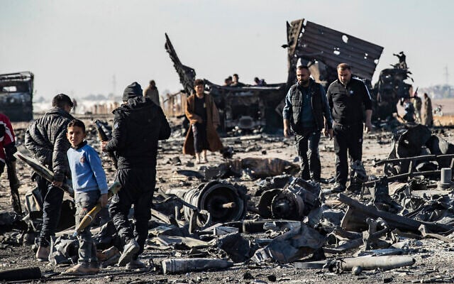 People pick up metal and unexploded ammunition from the site of the previous evening's Israeli airstrike that targeted shipments of weapons that belonged to Syrian government forces in Qamishli, in mainly Kurdish northeastern Syria, on December 10, 2024. (Delil Souleiman/AFP)