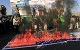 A banner depicting the flags of the US and Israel is burnt during a rally by supporters of Yemen's Houthi rebel group in solidarity "with the people of Gaza," in the Houthi-controlled capital Sanaa on December 13, 2024. (Mohammed Huwais/AFP)
