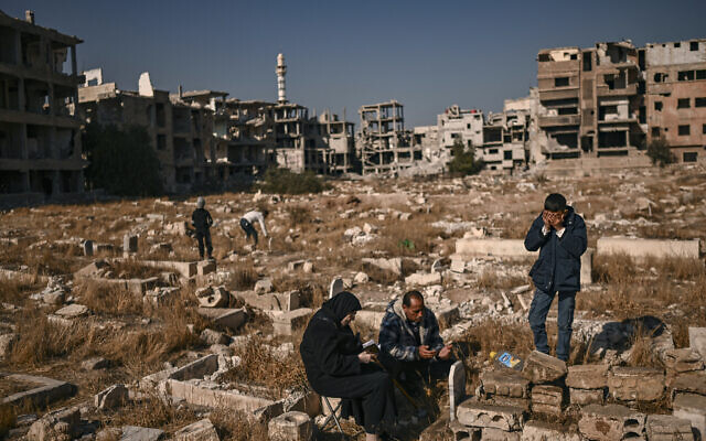 People pray by the grave of a relative in a damaged cemetery at the Yarmouk camp for Palestinian refugees in the south of Damascus on December 14, 2024. (Aris MESSINIS / AFP) People pray by the grave of a relative in a damaged cemetery at the Yarmouk camp for Palestinian refugees in the south of Damascus on December 14, 2024. (Aris MESSINIS / AFP)