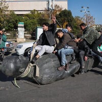 Students drag a toppled statue of late president Hafez al-Assad on the street during a rally near the campus of the Damascus University in the Syrian capital on December 15, 2024. (Omar HAJ KADOUR / AFP)