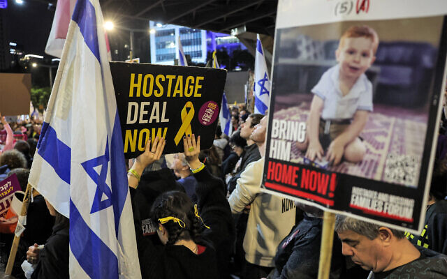 Demonstrators hoist signs during an anti-government protest calling for the release of hostages, outside the IDF headquarters in Tel Aviv, December 21, 2024. (Jack Guez / AFP)