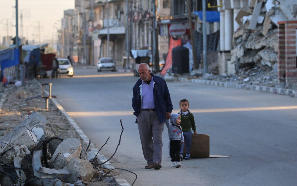 A Palestinian man walks with children in Deir el-Balah in the central Gaza Strip, on December 24, 2024. (Eyad BABA / AFP)