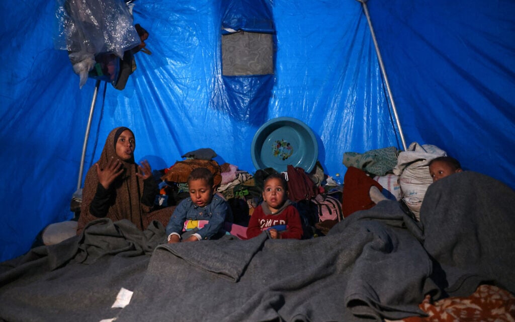 A woman sits next to her children inside a shelter at a camp for displaced Palestinians in Khan Younis, in the southern Gaza Strip on December 29, 2024 (BASHAR TALEB / AFP)