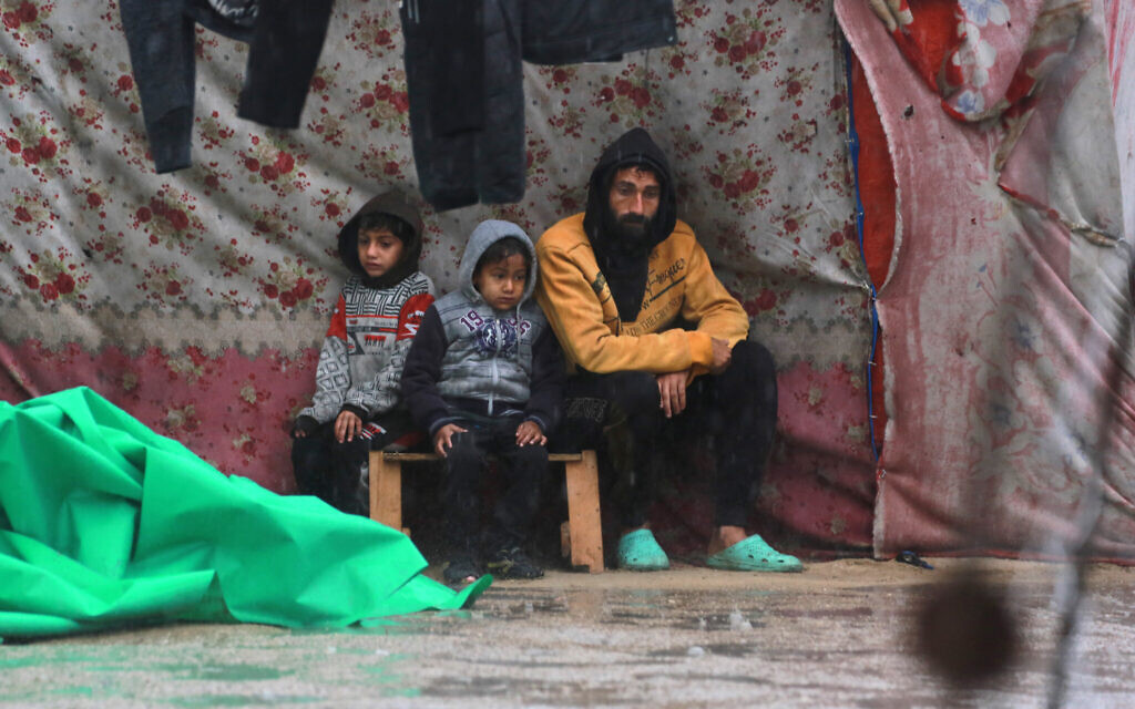 Palestinians take shelter from the rain at a makeshift camp housing displaced Palestinians in Khan Younis, in the southern Gaza Strip on December 31, 2024 (Photo by BASHAR TALEB / AFP)