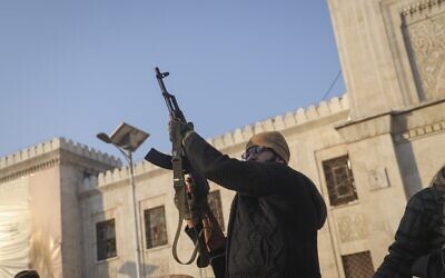 An opposition fighter fires his AK-47 in the air in celebration in Hama, Syria, December 6, 2024.(AP Photo/Omar Albam)