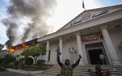 Opposition fighters celebrate as they burn down a military court in Damascus, Syria, Sunday, December 8, 2024. (AP Photo/Hussein Malla)