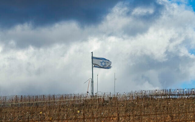 An Israeli flag waves on the top of a hill near the so-called Alpha Line that separates the Israeli side of the Golan Heights from Syria, in the town of Majdal Shams, December 13, 2024. (AP Photo/Matias Delacroix)