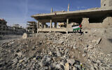 Palestinian boys carry their national flag, as they stand on the rubble of buildings destroyed during the Syrian civil war and also demolished by the Damascus government or stripped by thieves, at the Palestinian refugee camp of Yarmouk, outside Damascus, Syria, December 14, 2024. (Hussein Malla/AP)