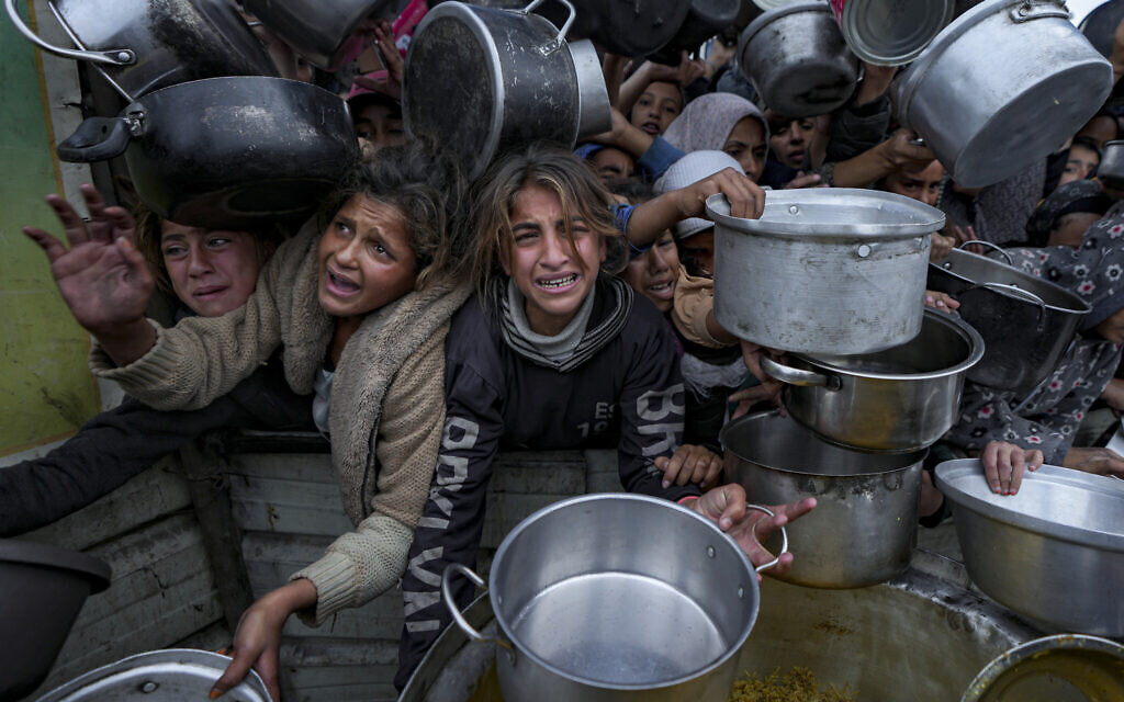 Palestinian women and girls struggle to reach for food at a distribution center in Khan Younis, Gaza Strip, Dec. 20, 2024. (AP Photo/Abdel Kareem Hana)