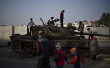 Children on the top of an ousted Syrian government forces tank that was left on a street in an Alawite neighborhood, in Homs, Syria, December 26, 2024. (AP Photo/ Leo Correa)