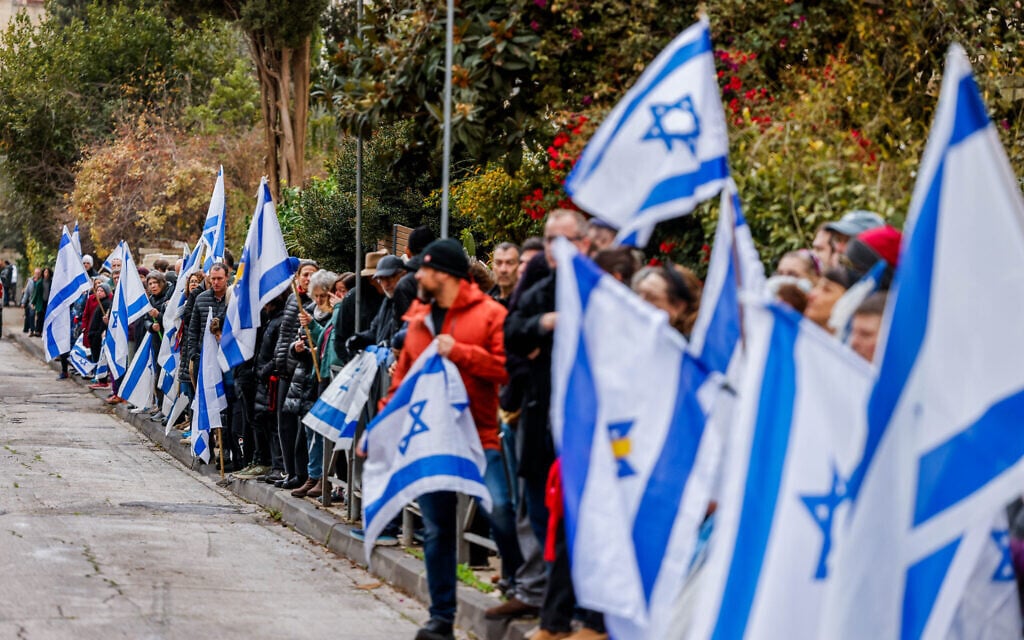 People holding Israeli flags as they pay their respect to Staff Sgt. Yuval Shoham who was killed in the Gaza Strip outside his home in Jerusalem, December 30, 2024 (Chaim Goldberg/Flash90)