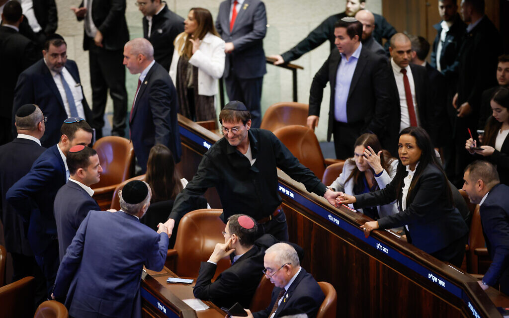 Likud MK Boaz Bismuth, center, greets other lawmakers after arriving at the Knesset from sitting shiva following the death of his mother, on December 31, 2024. His shirt is torn in line with Jewish mourning customs. (Knesset spokesperson)