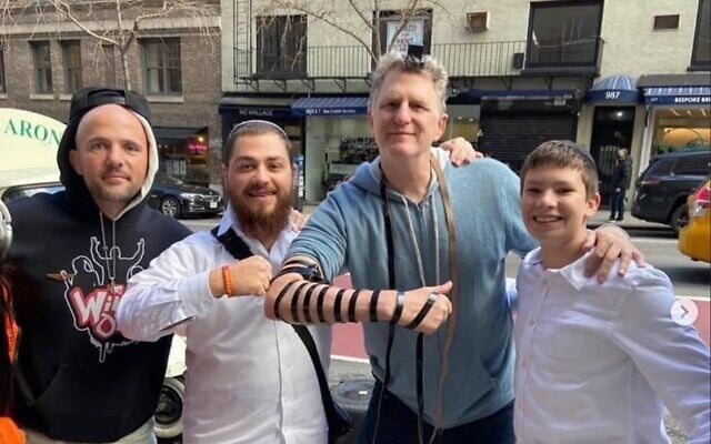 Yossi Farro, center, finds himself between Jewish rapper Kosha Dillz, left, and actor Michael Rapaport, while facilitating the donning of tefillin. (Courtesy)