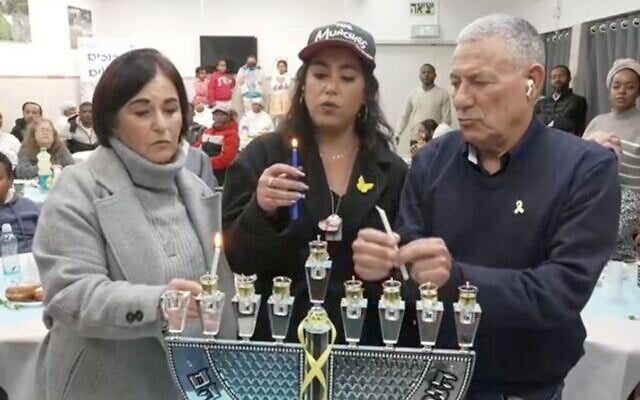 Hostage Matan Tzangauker's girlfriend Ilana Gritzewsky (c) lights Hanukkah candles with Jewish Agency chief Doron Almog on December 31, 2024. (Screen capture/Channel 12)