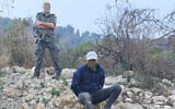 A volunteer from the Border Police with a suspect apprehended while attempting to loot the Horbat Binit site in the lower Galilee, in an image released on December 23, 2024. (courtesy Israel Antiquities Authority)