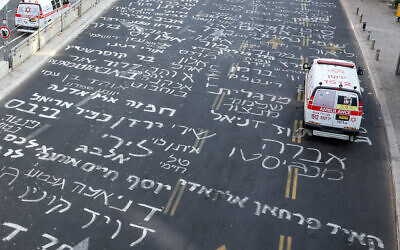 An ambulance is parked by a bus stop on a road inscribed with the names of Israeli hostages held in the Gaza Strip since the October 7, 2023, Hamas atrocities, outside the Defense Ministry headquarters in Tel Aviv on August 24, 2024. (Jack Guez/AFP)