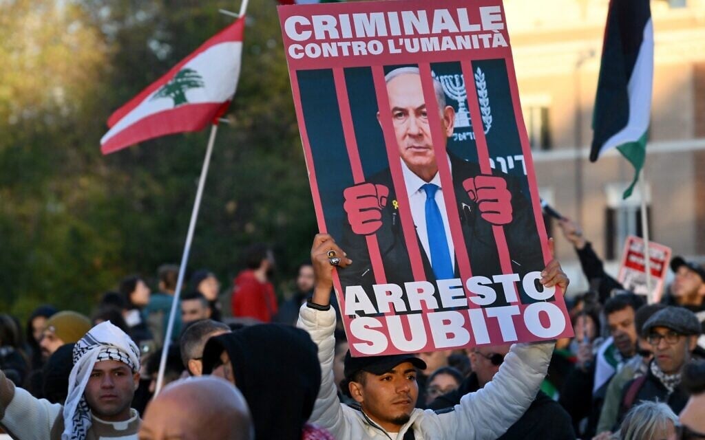 A demonstrator holds up a placard with Prime Minister Netanyahu behind bars and Italian for, 'Criminal against humanity, let's arrest him now,' at an anti-Israel rally in Rome on November 30, 2024. (Alberto PIZZOLI / AFP) A demonstrator holds up a placard with Prime Minister Netanyahu behind bars and Italian for, 'Criminal against humanity, let's arrest him now,' at an anti-Israel rally in Rome on November 30, 2024. (Alberto PIZZOLI / AFP)
