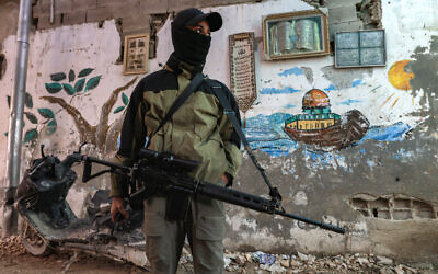 A Palestinian gunman stands guard with an assault rifle along an alley in the Jenin refugee camp in the northern West Bank on December 29, 2024.(Jaafar Ashtiyeh/AFP)