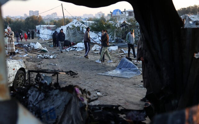 Palestinians walk amid scattered debris of tents on January 2, 2025, following an overnight Israeli strike on a makeshift displacement camp in al-Mawasi in the southern Gaza Strip, that reportedly killed at least 11 people, including the chief of the Hamas police chief and his deputy. (Photo by BASHAR TALEB / AFP)