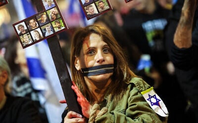 A protester with her hands bound and mouth taped shut holds a placard during a demonstration calling for the release of hostages held captive in Gaza by Hamas terrorists since the October 7 attacks, outside the Defense Ministry headquarters in Tel Aviv on January 4, 2025. (Jack Guez / AFP)