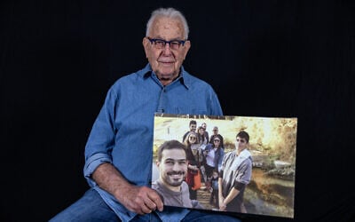 Holocaust survivor Naftali Furst holds a family photo taken in Israel, as he poses in his home in the northern Israeli city of Haifa, on November 28, 2024. (MENAHEM KAHANA / AFP)