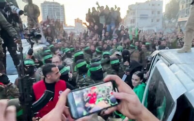 Hamas terrorists hand over hostages Emily Damari (in green sweater), Doron Steinbrecher and Romi Gonen, abducted during the October 7, 2023, massacre in southern Israel, to members of the International Committee of the Red Cross (ICRC), as part of a ceasefire and a hostage-security prisoners deal, in Gaza City, January 19, 2025 (AFPTV / AFP)